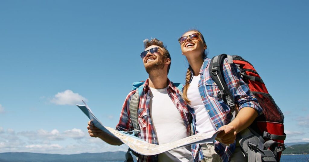 A US expat couple holds a map and smiles off in the distance.