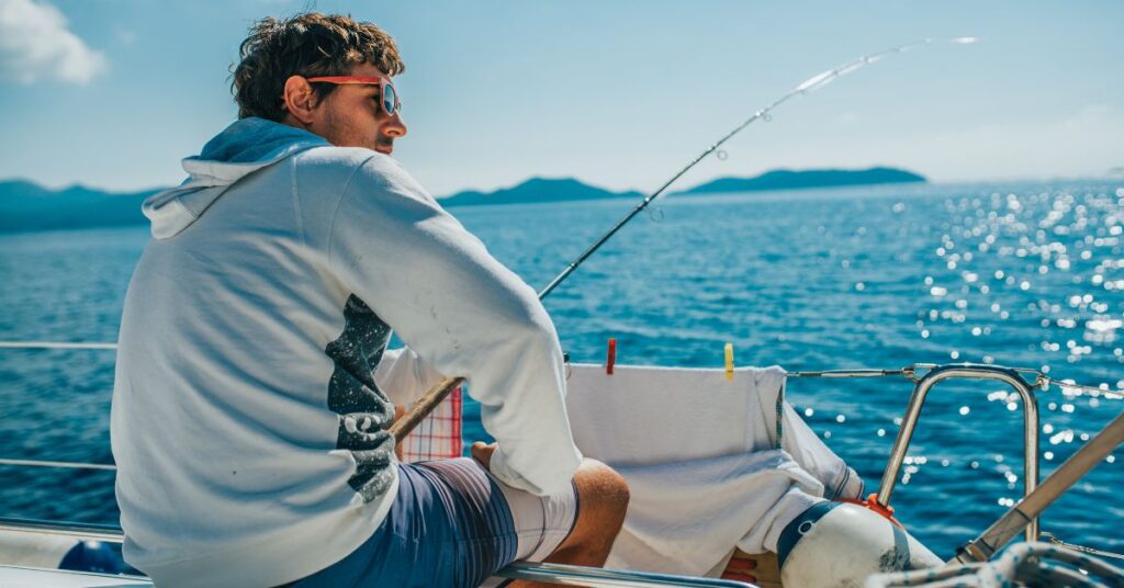 Young man fishes off a sailboat in Croatia