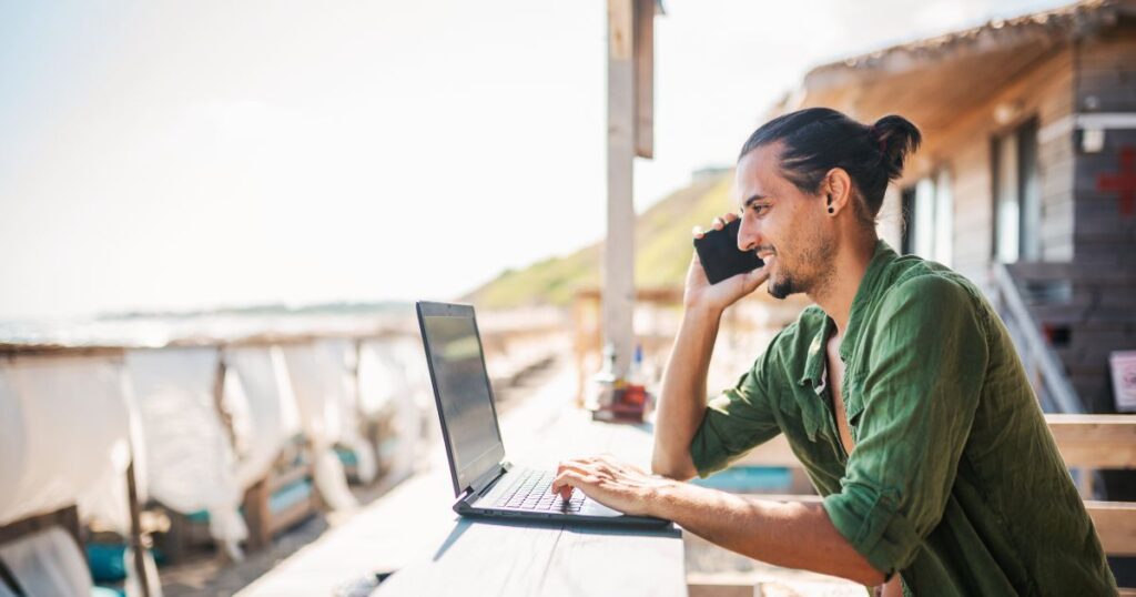 Digital nomad on the phone in Bali looking at his laptop.