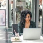 US expat researches, "How to file an amended return" on her laptop on an outdoor terrace.