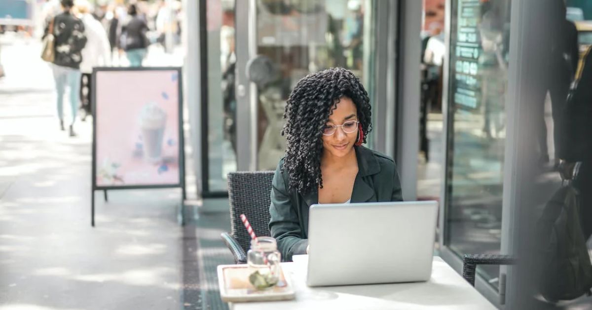 US expat researches, "How to file an amended return" on her laptop on an outdoor terrace.