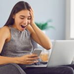 A US expat looking at her laptop in surprise because she has just won the lottery and needs to pay taxes on lottery winnings.