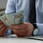 US expat counting hundred-dollar bills in preparation for sending large sums of money overseas.