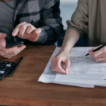 Two people sitting at a wooden desk checking for FATCA exemptions